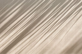 Soft beige texture with natural light and shadows for Assoluto Studio homepage.