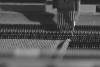 Close-up of Italian knitwear craftsmanship with Fedeli textile machine in motion.