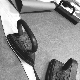 Traditional artisan tools pressing organic silk garments by HERTH, showcasing Italian craftsmanship and attention to detail at Assoluto Studio.