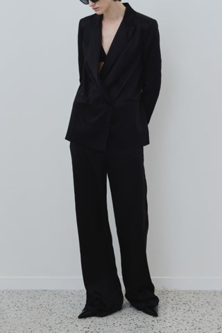 Model wearing the HERTH Joy trousers with the Uma blazer in black. Available at ASSOLUTO boutique in Rome.